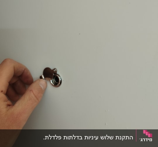 יד מחזיקה מכסה חור מנעול על דלת